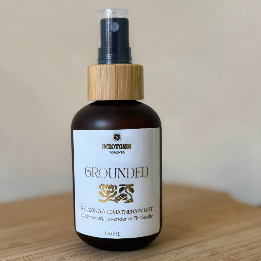 Aromatherapy mist bottle labeled 'Grounded' on a wooden surface with a neutral background