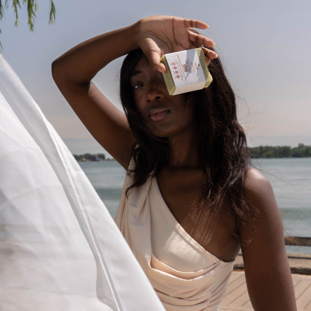 Beautiful woman holding up a bar of Unwind Serotonin hemp soap bar.